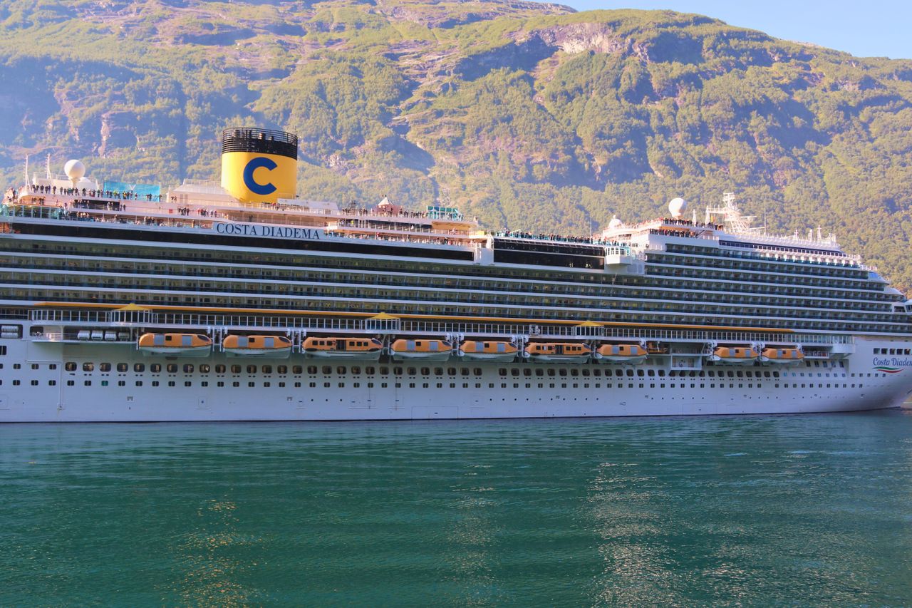 Scenic view of a cruise ship in a Norwegian fjord with green mountains.